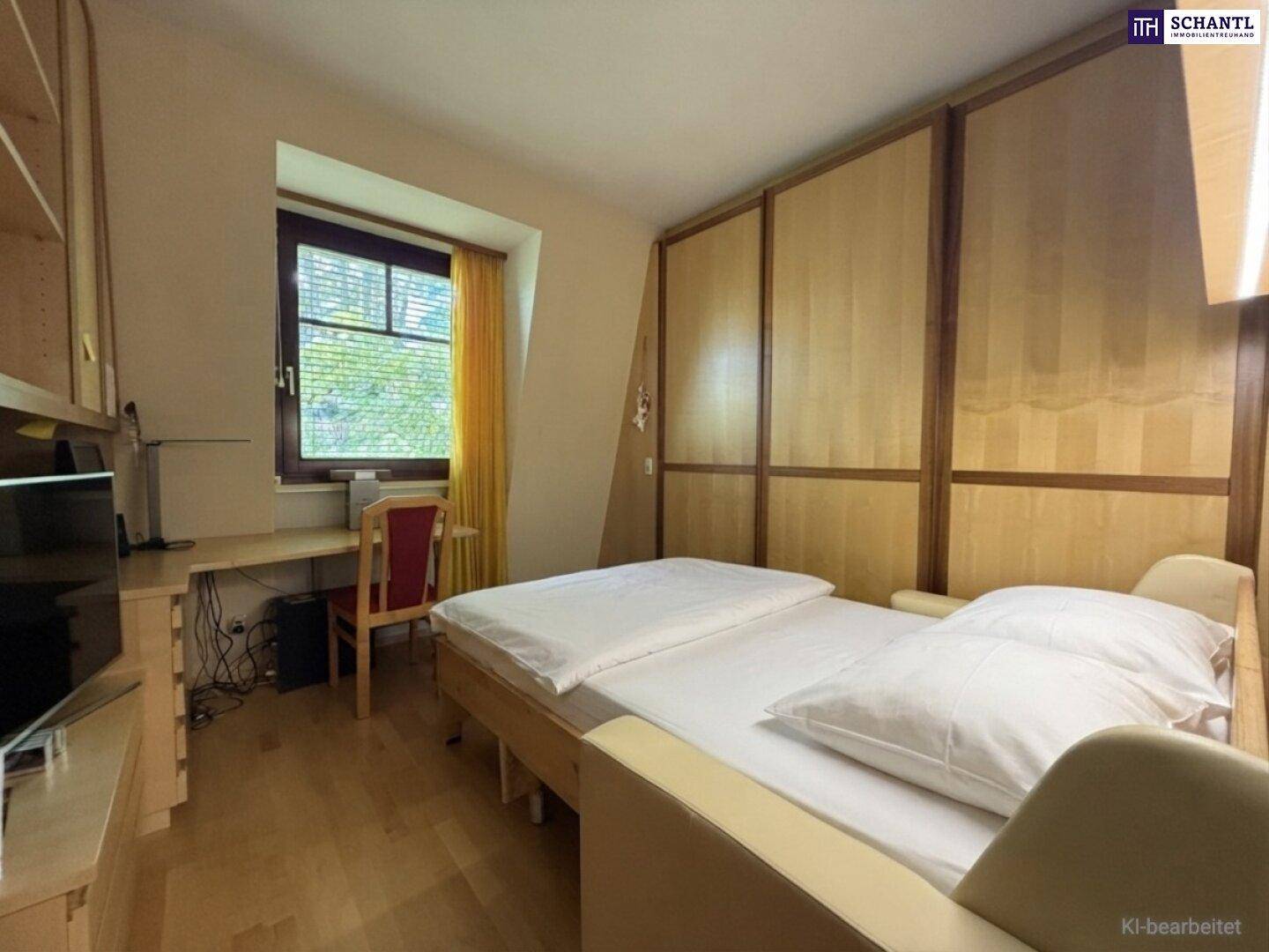 Helles Schlafzimmer mit Einzelbett, Holzvertäfelung und einem Arbeitsbereich am Fenster.