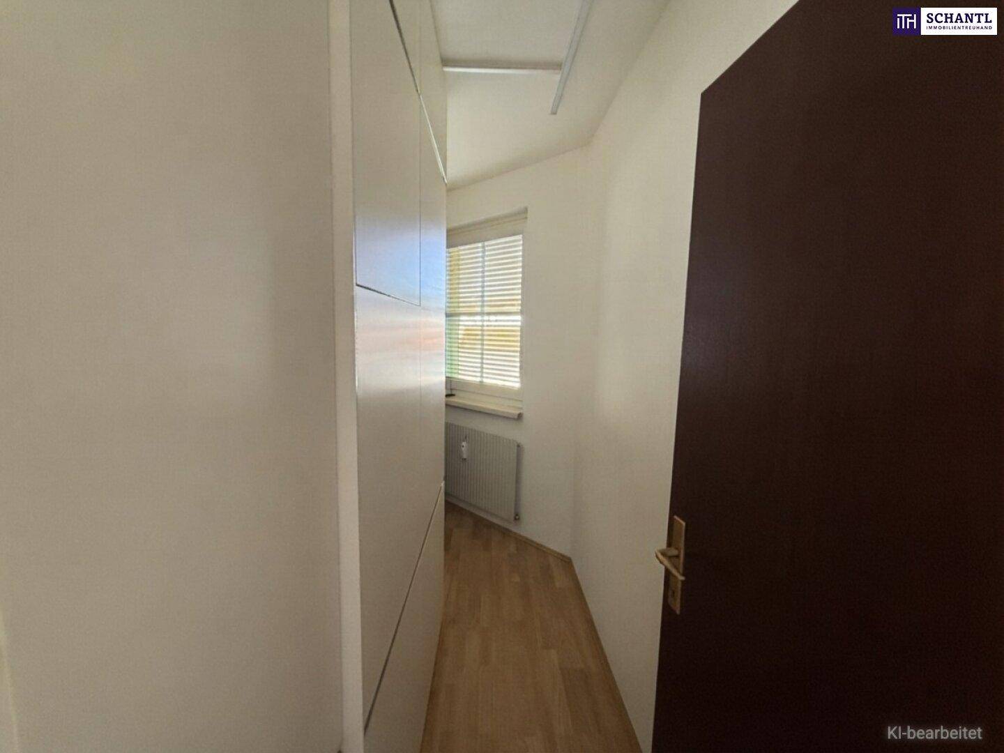 Schmaler Flur mit integrierten weißen Schränken und einem Fenster am Ende, bietet Stauraum.