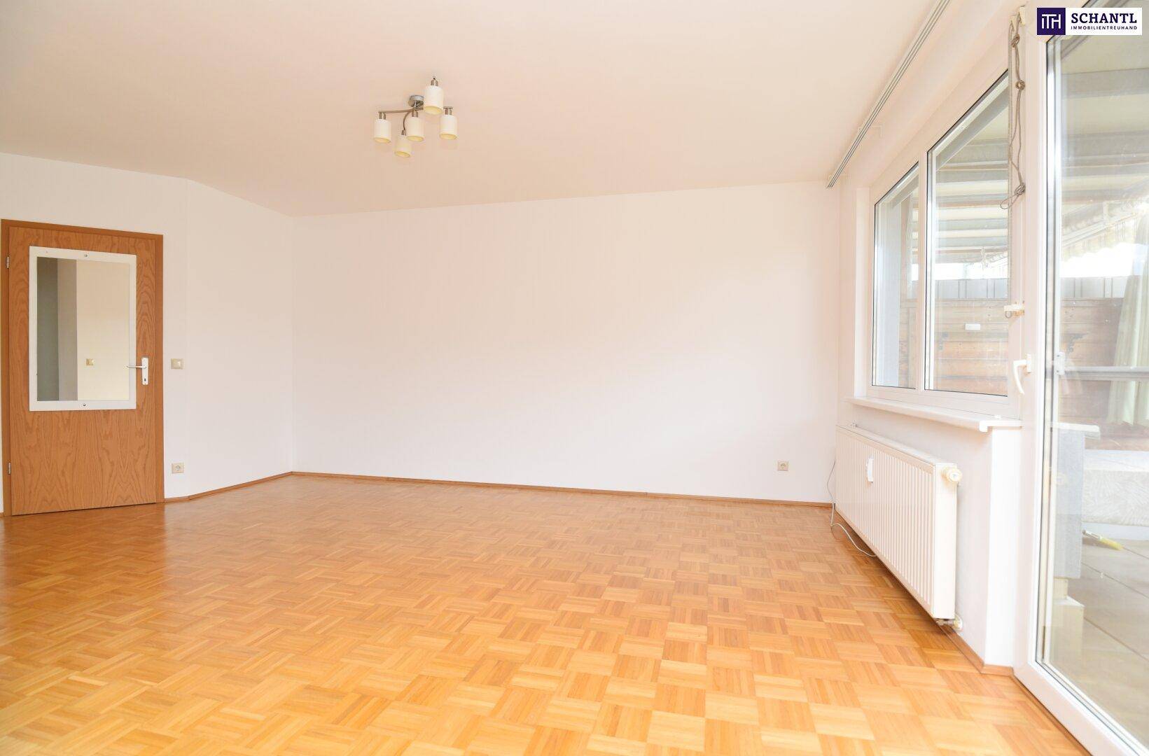 Helles Wohnzimmer mit Parkettboden und Zugang zur Terrasse oder zum Garten.