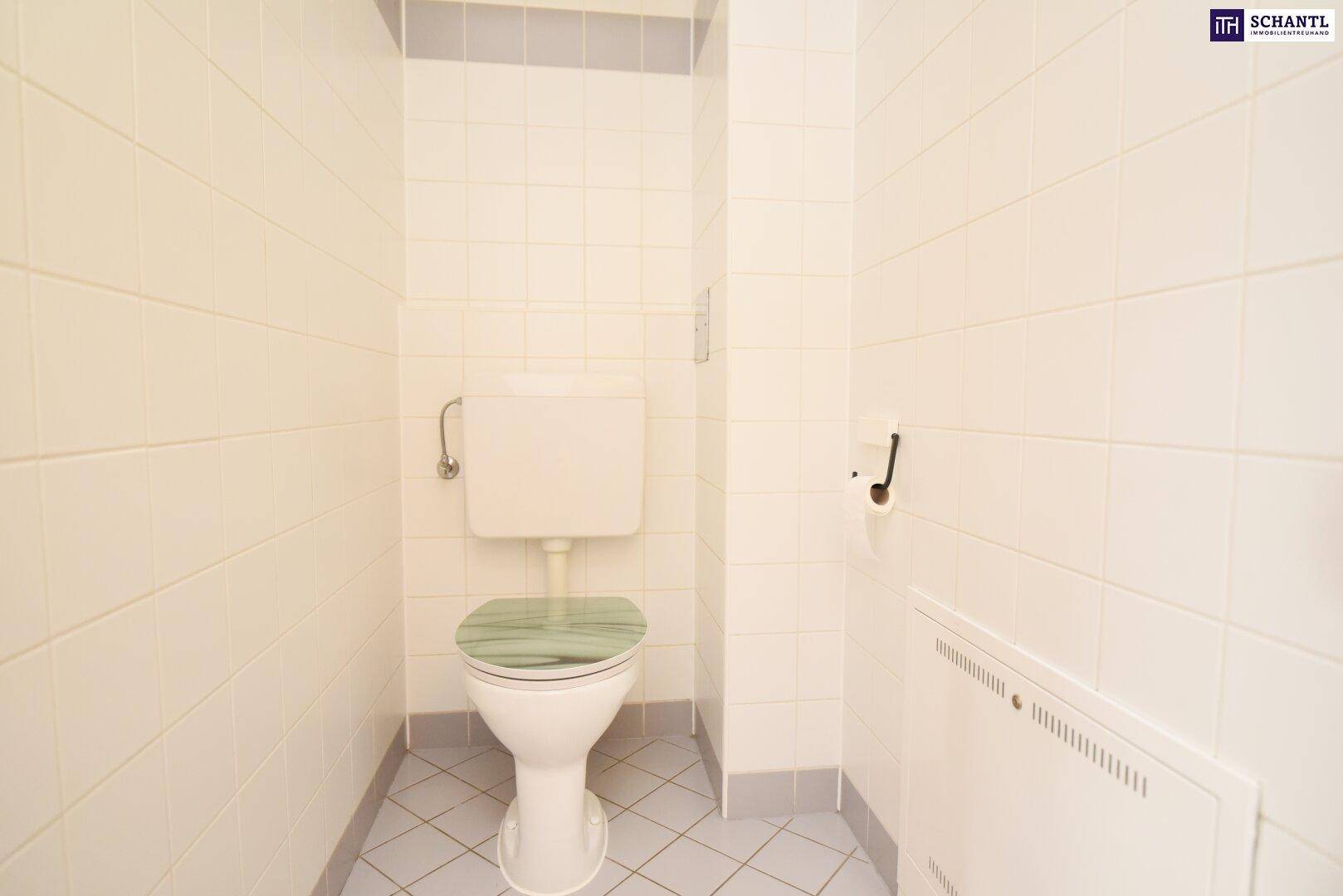 Separates WC mit Fliesenboden und Wandheizkörper.
