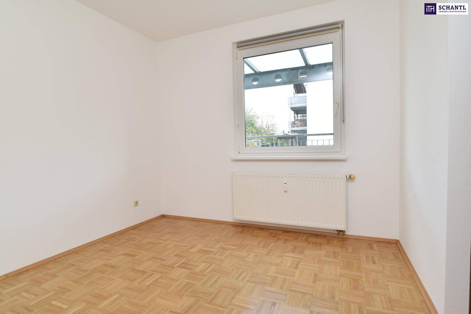 Helles Schlafzimmer mit Parkettboden und großem Fenster, das viel Tageslicht bietet.