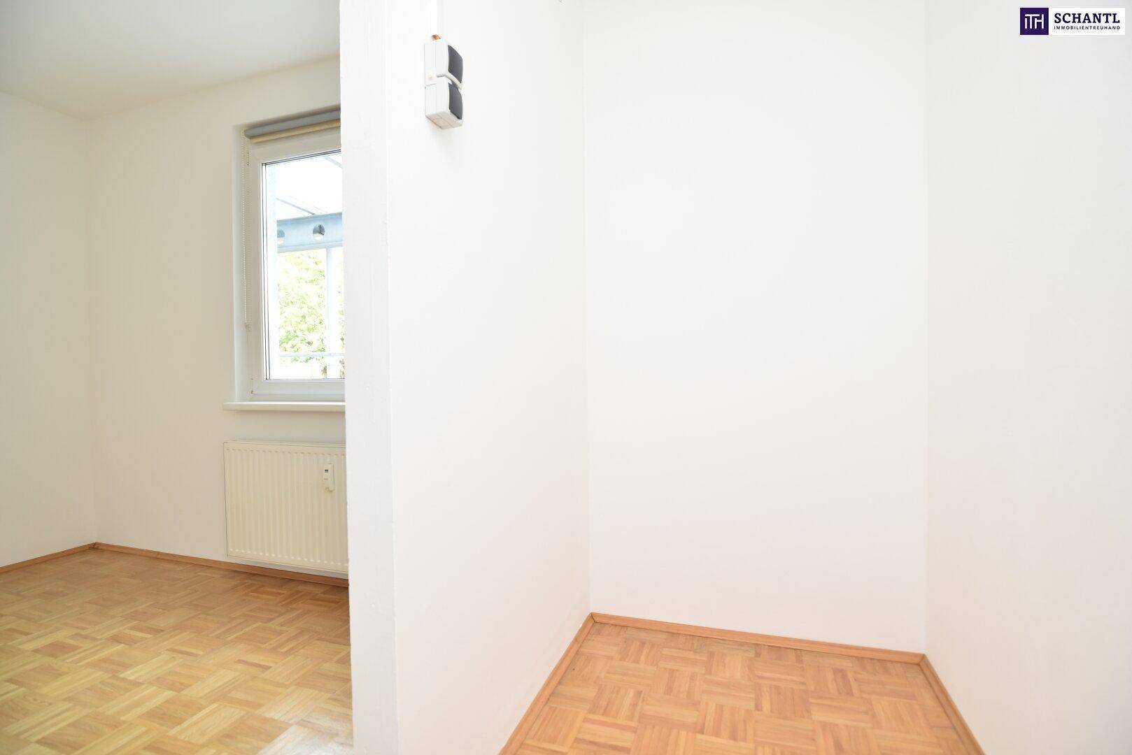 Helles Zimmer mit Parkettboden und Fenster, das viel Tageslicht hereinlässt.