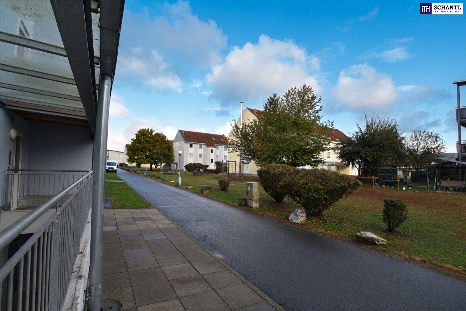 Außenansicht einer Wohnsiedlung mit Wegen, Gebäuden und Grünflächen.