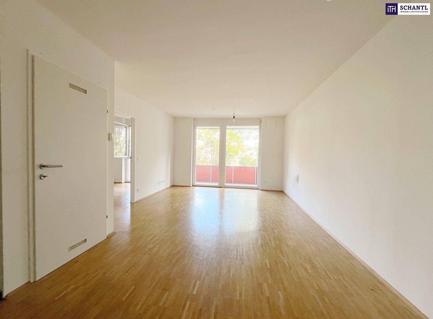 Heller Wohnbereich mit Parkettboden und Zugang zu einem Balkon, der viel Tageslicht hereinlässt.