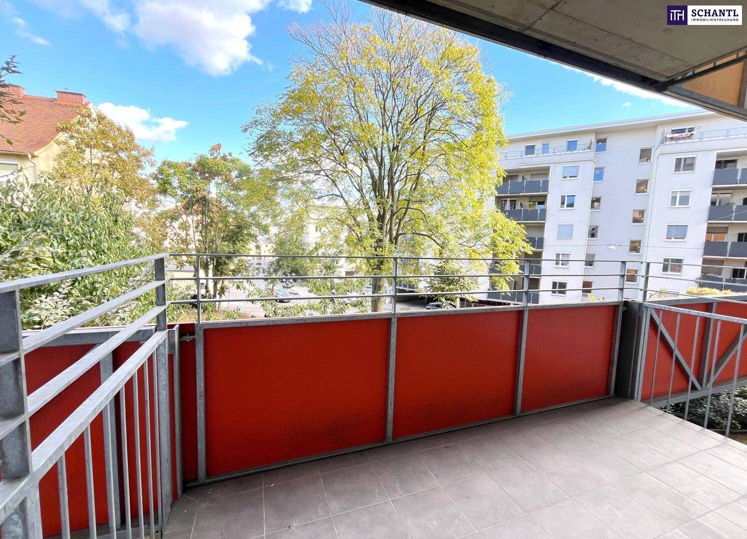 Balkon mit Blick auf grüne Bäume und umliegende Gebäude, bietet eine angenehme Aussicht.
