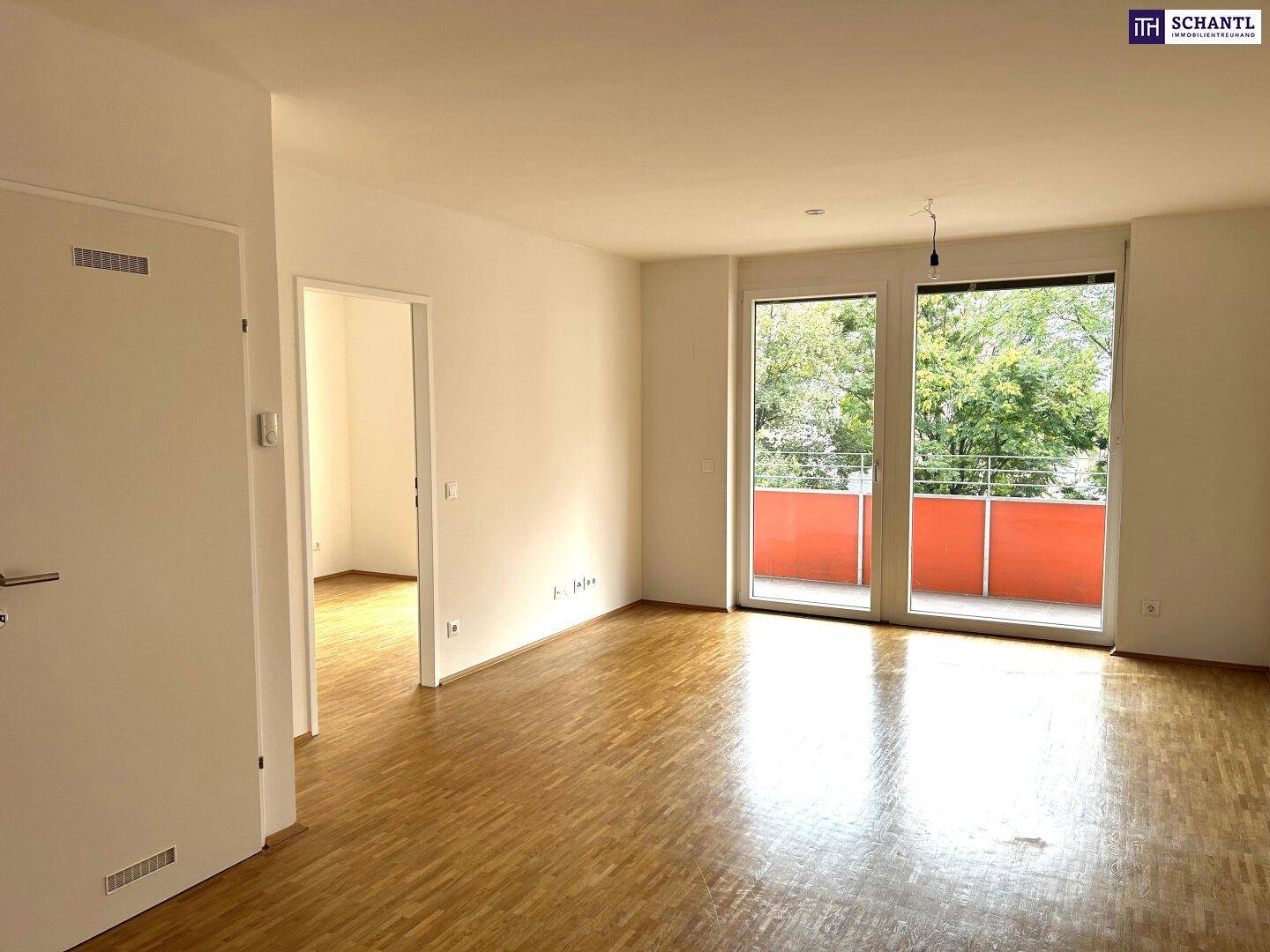 Heller Wohnraum mit Parkettboden und Zugang zu einem Balkon, ideal für entspannte Stunden.