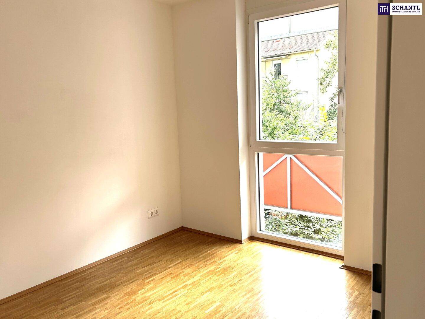 Gemütliches Schlafzimmer mit Parkettboden und Fenster, das einen Blick ins Grüne bietet.
