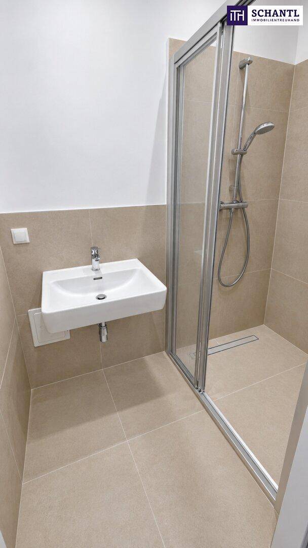 Modernes Badezimmer mit beigen Fliesen, Waschbecken und ebenerdiger Dusche.