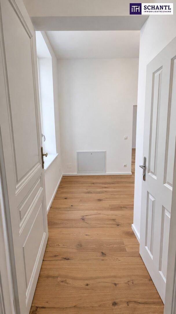 Heller Flur mit Holzboden und weißen Türen, der zu weiteren Räumen führt.