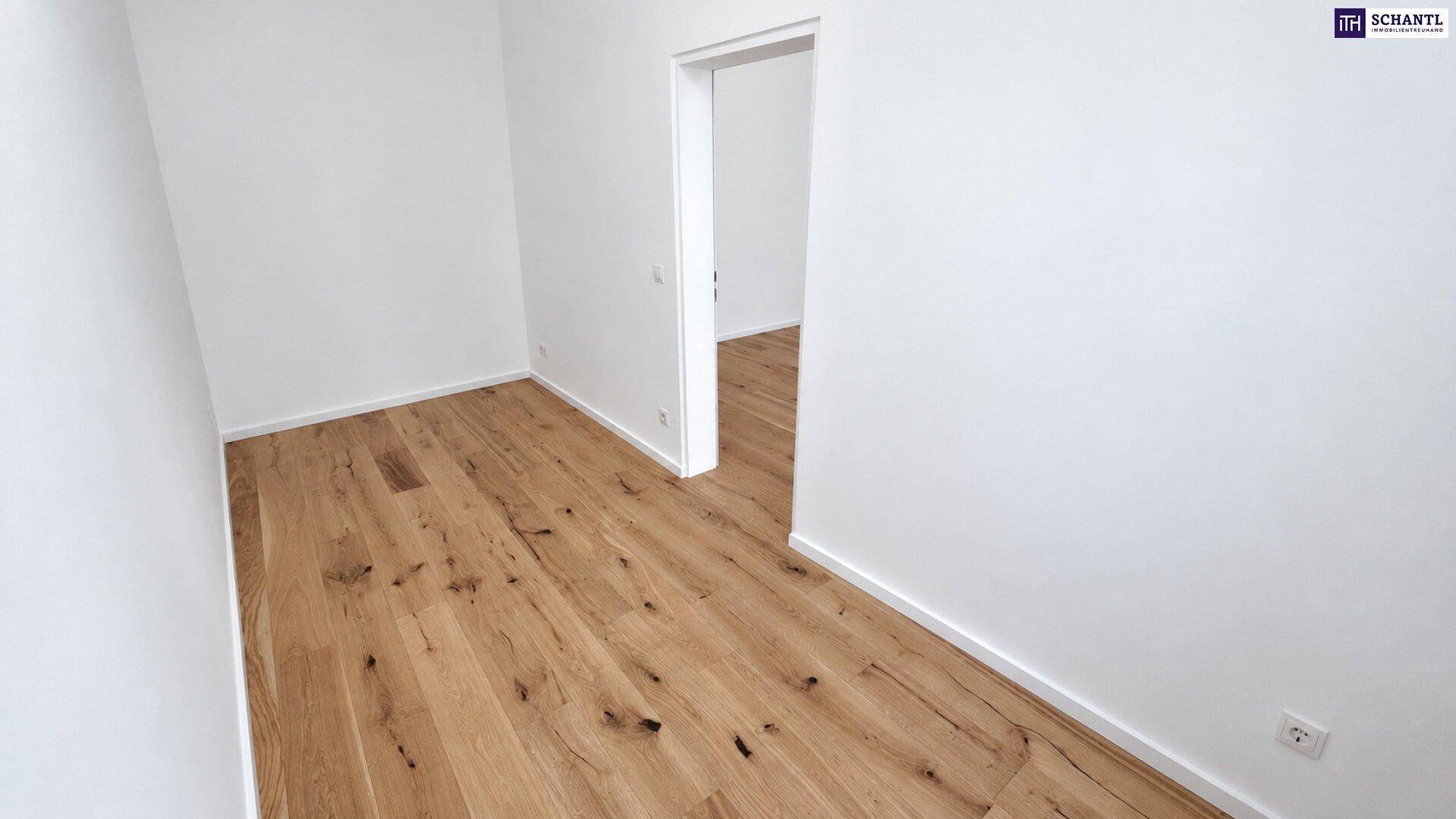 Leerer Raum mit Holzboden und weiß gestrichenen Wänden, der zu einem weiteren Zimmer führt.