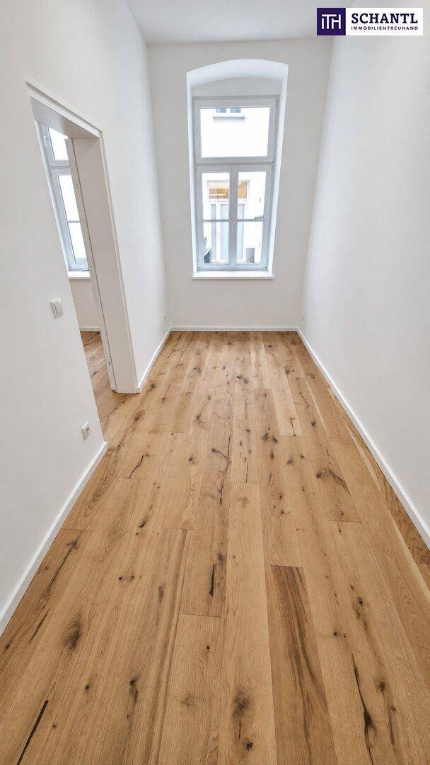 Schmaler Raum mit Holzboden und einem Fenster, ideal als Durchgangszimmer oder kleines Büro.