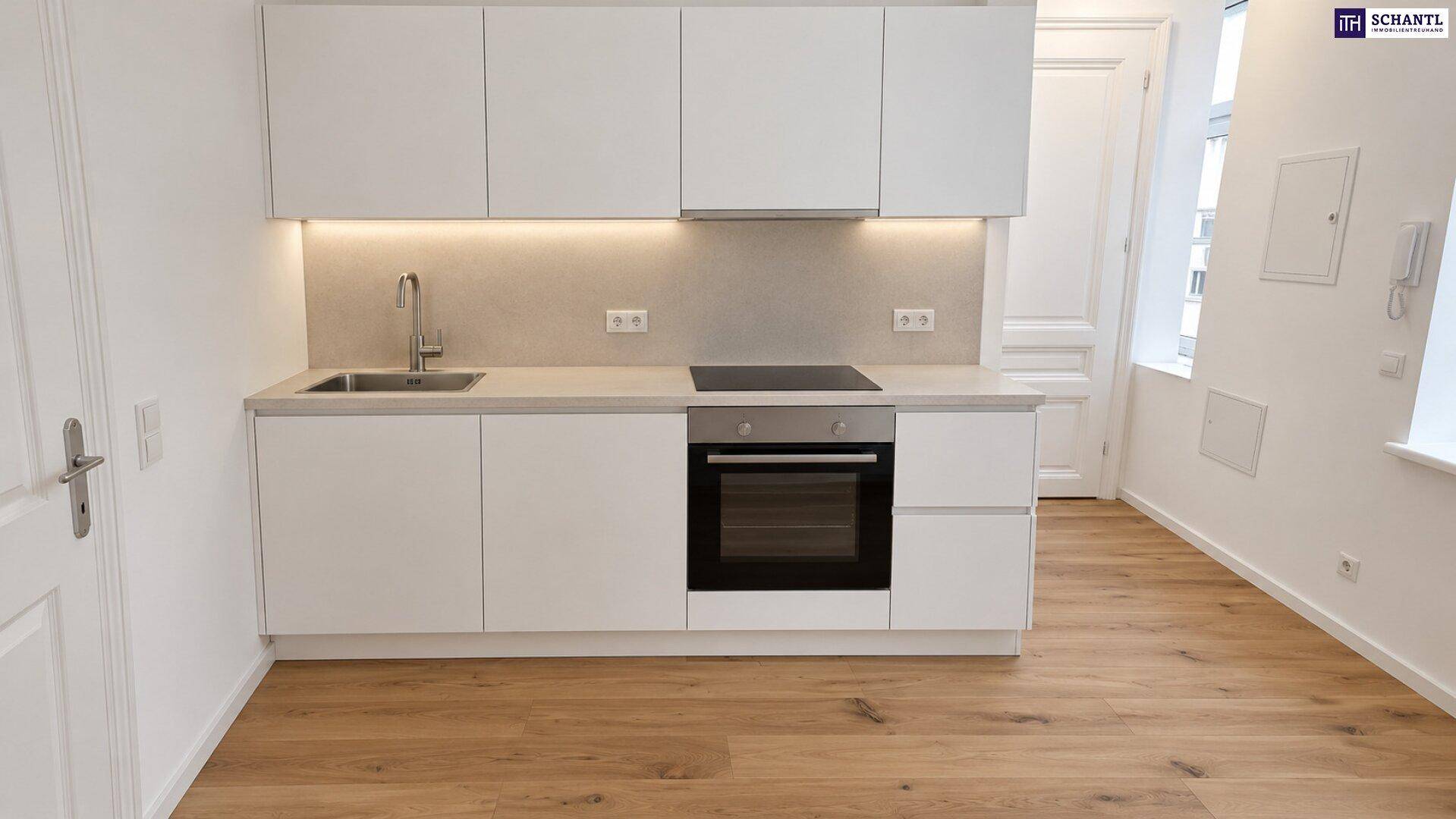 Moderne Einbauküche mit weißen Schränken, integrierten Geräten und Holzboden.