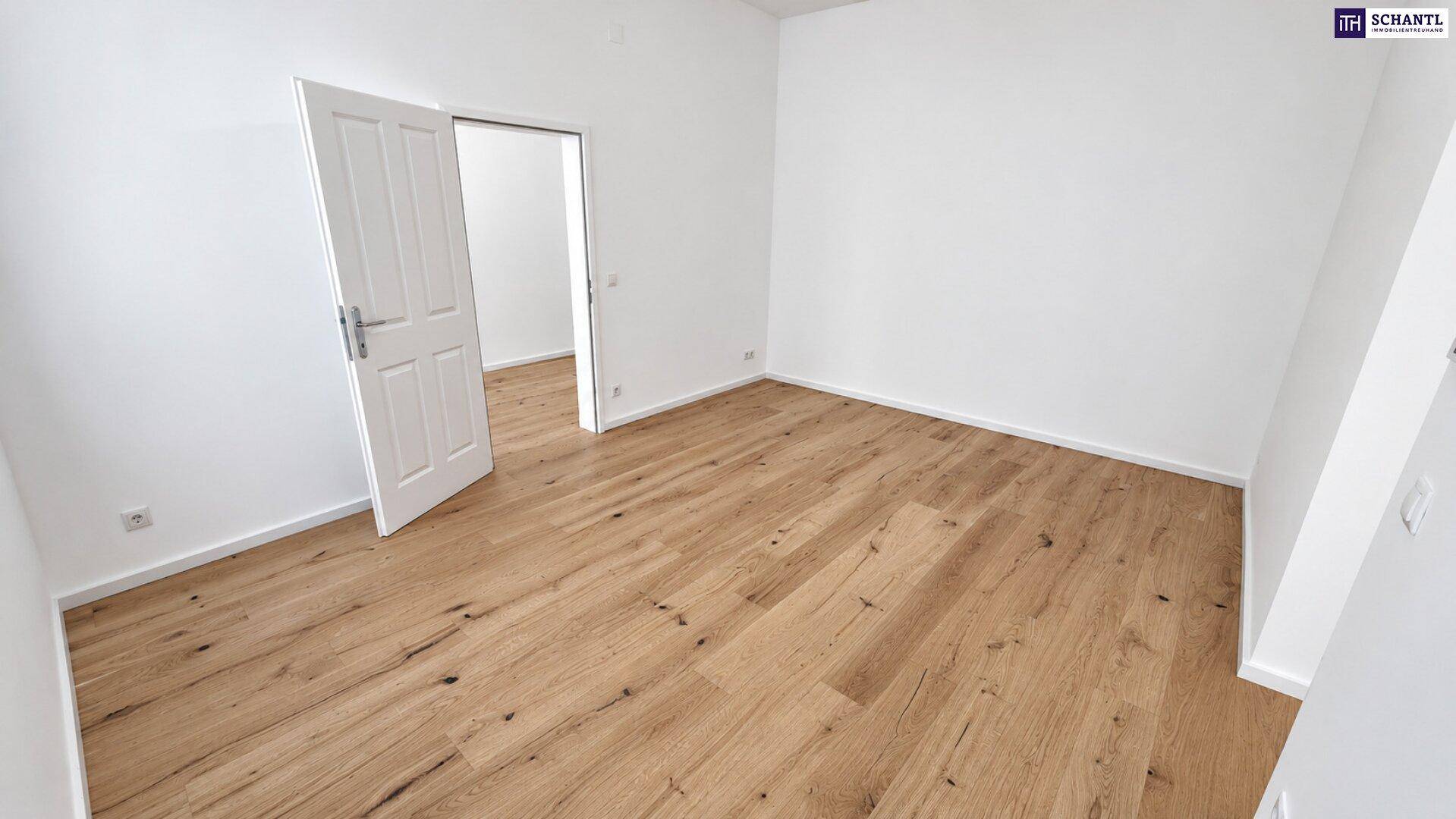 Leeres Zimmer mit Holzboden und weiß gestrichenen Wänden, bereit zur Einrichtung.