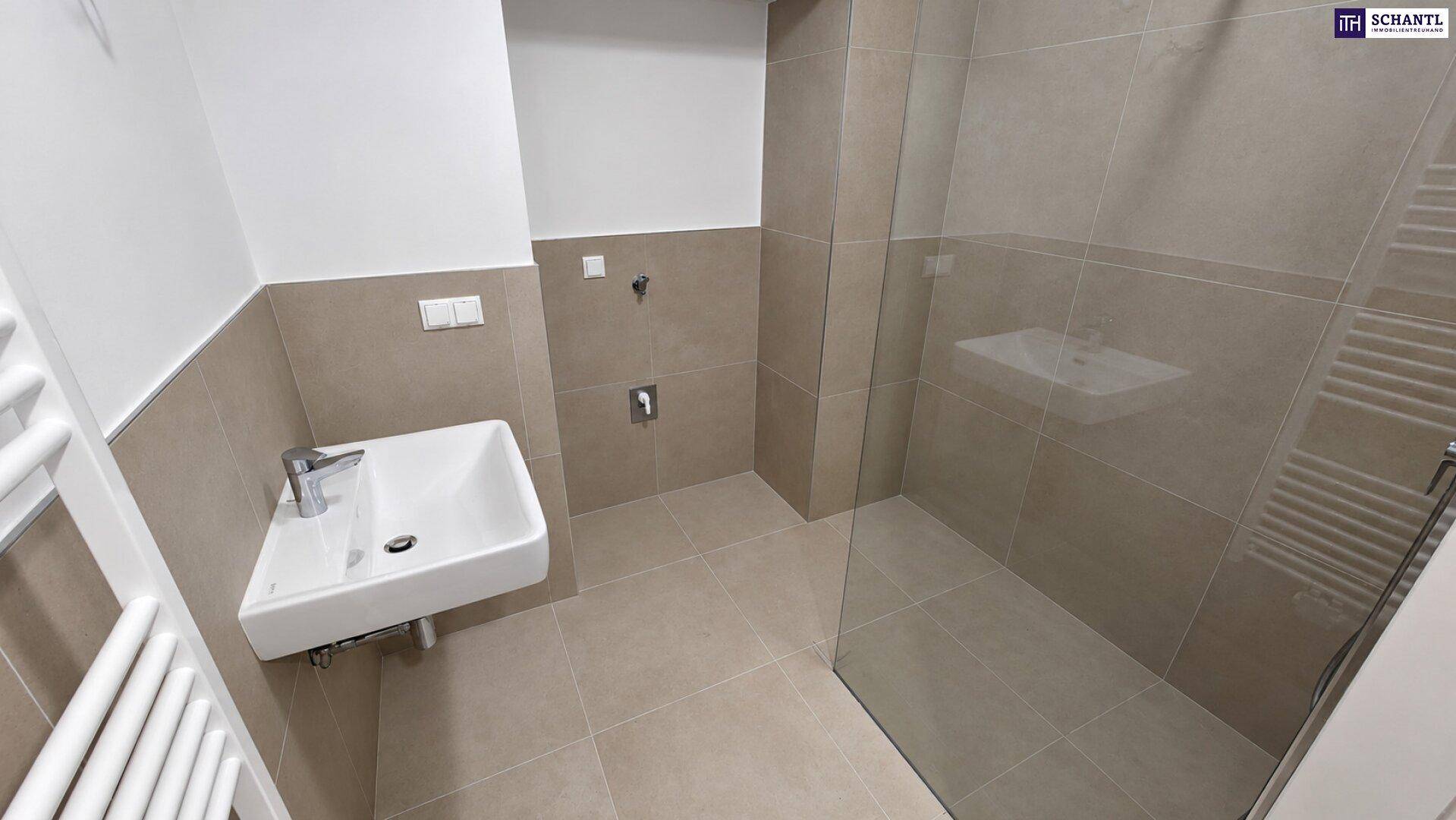 Modernes Badezimmer mit Waschbecken, ebenerdiger Dusche und beheiztem Handtuchhalter.