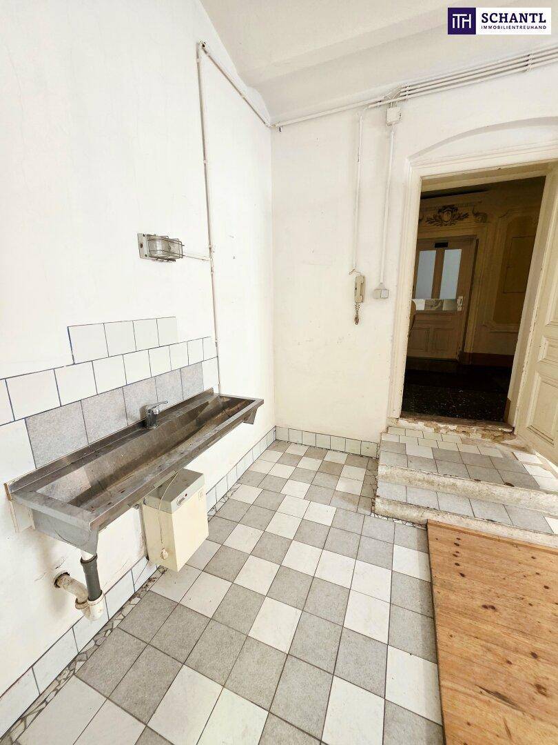 Kleiner Hauswirtschaftsraum mit kariertem Fliesenboden, einem Metallwaschbecken und weißen Wandfliesen.