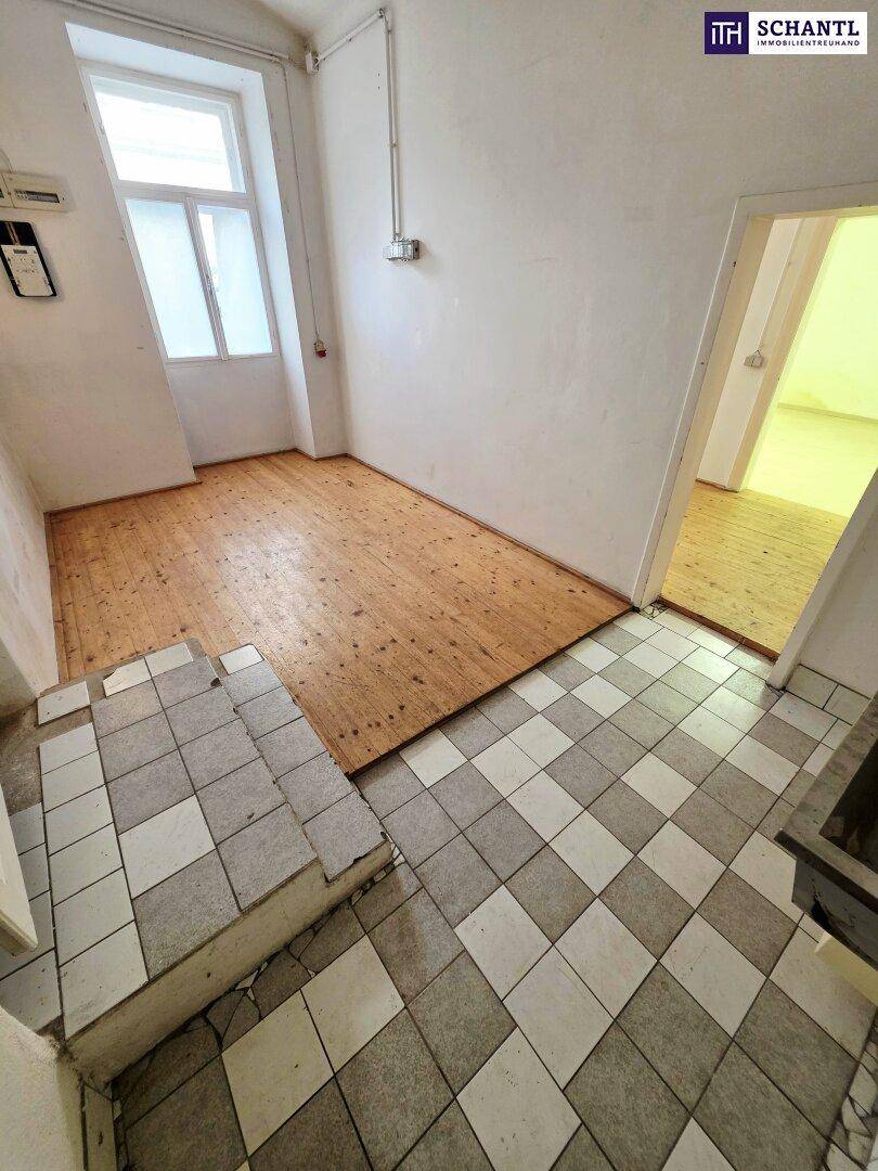 Übergangsbereich mit Stufen, der einen karierten Fliesenboden mit einem rustikalen Holzplankenboden verbindet.