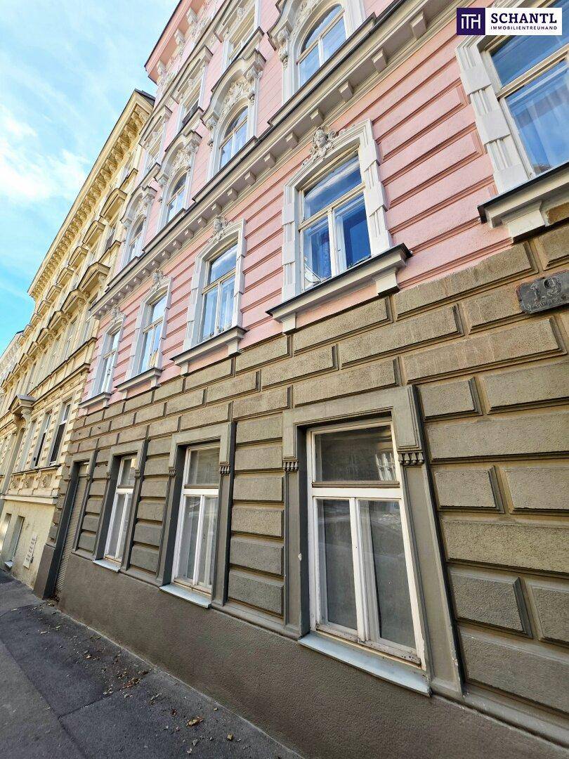 Ansicht der rosafarbenen Fassade eines Altbaus mit großen Fenstern im Erdgeschoss und darüber.