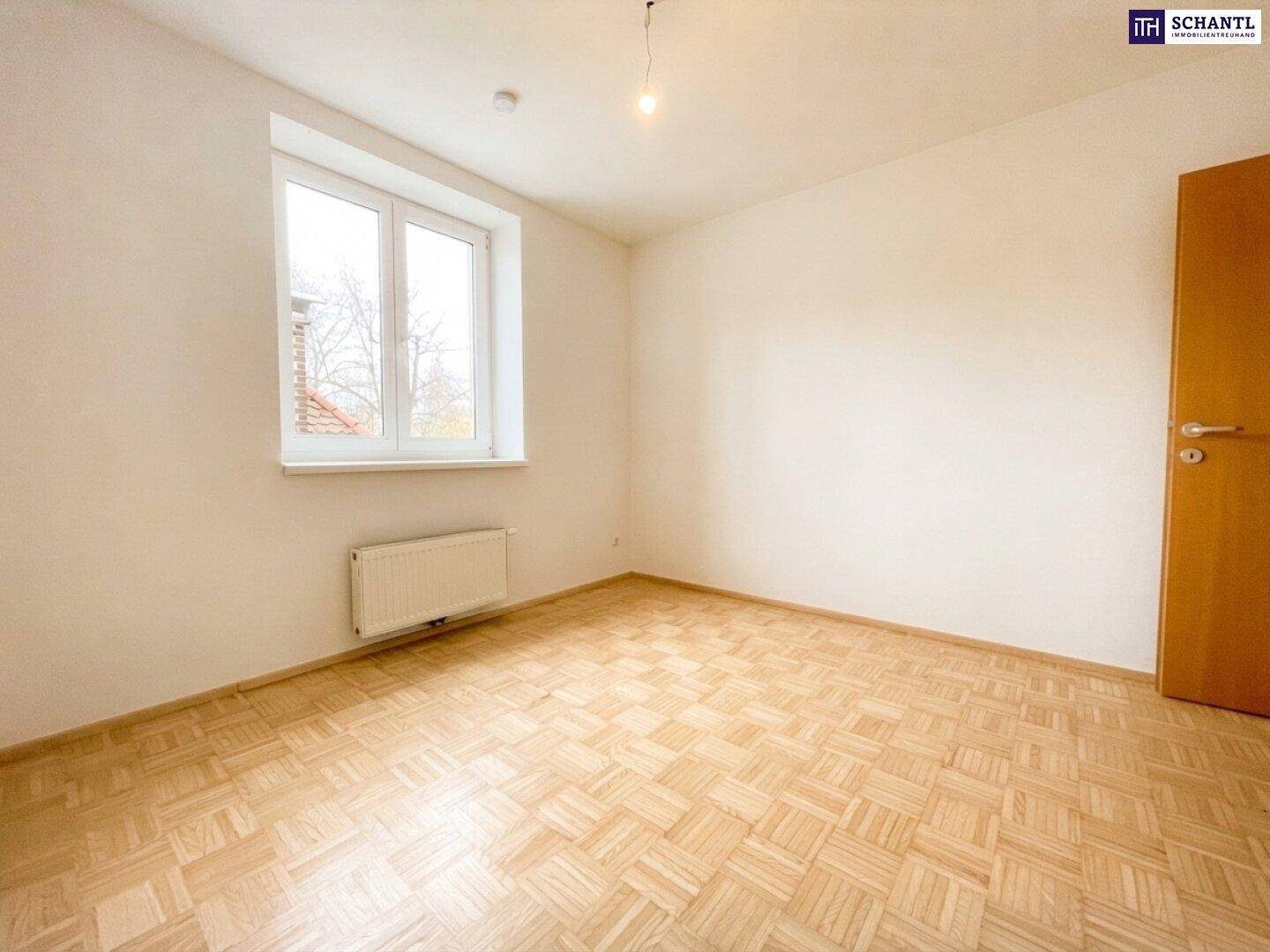 Helles Zimmer mit Parkettboden und großem Fenster, ideal als Schlaf- oder Arbeitszimmer.