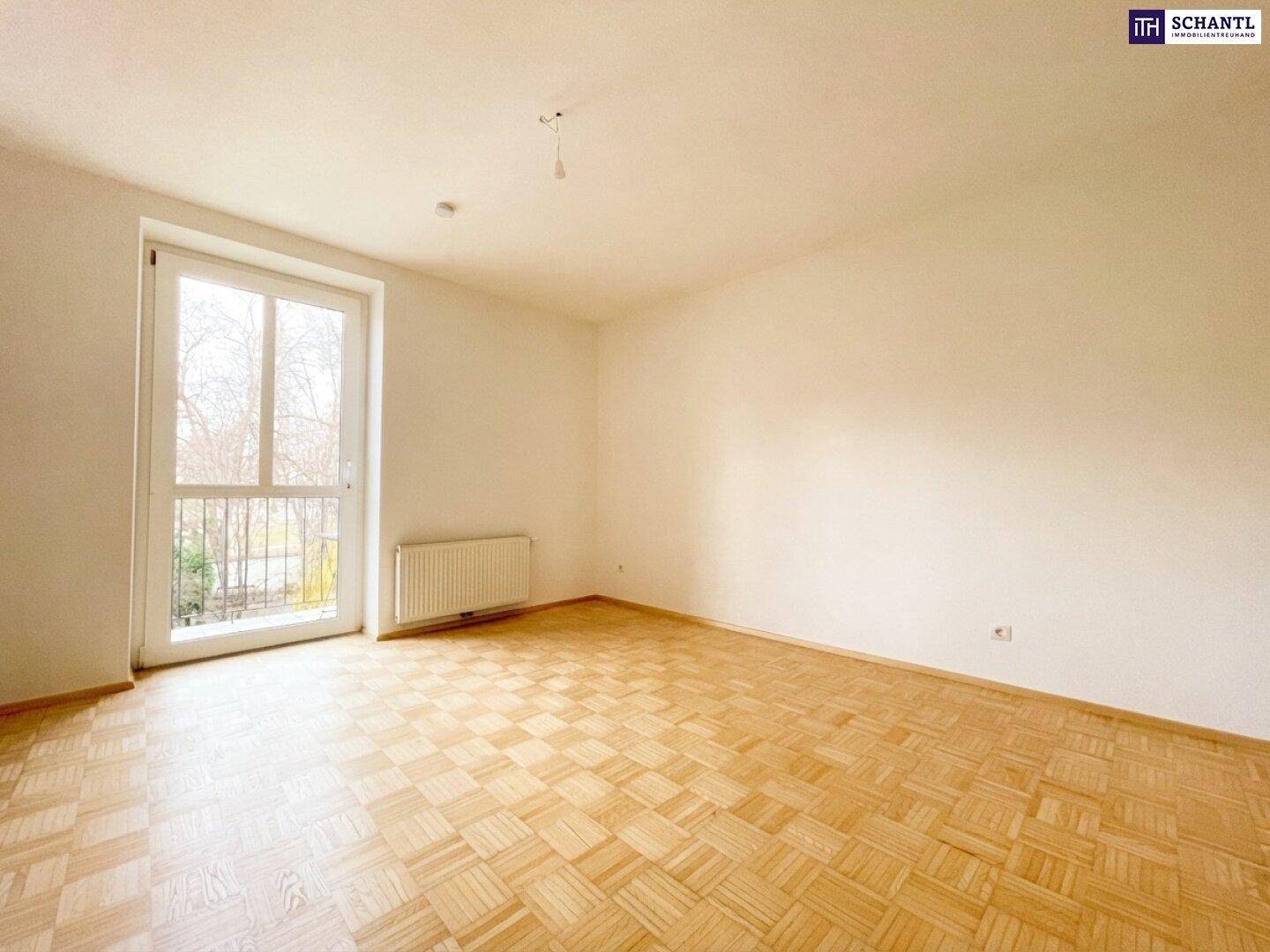 Geräumiges Zimmer mit Parkettboden und Zugang zum Balkon, bietet viel Tageslicht.