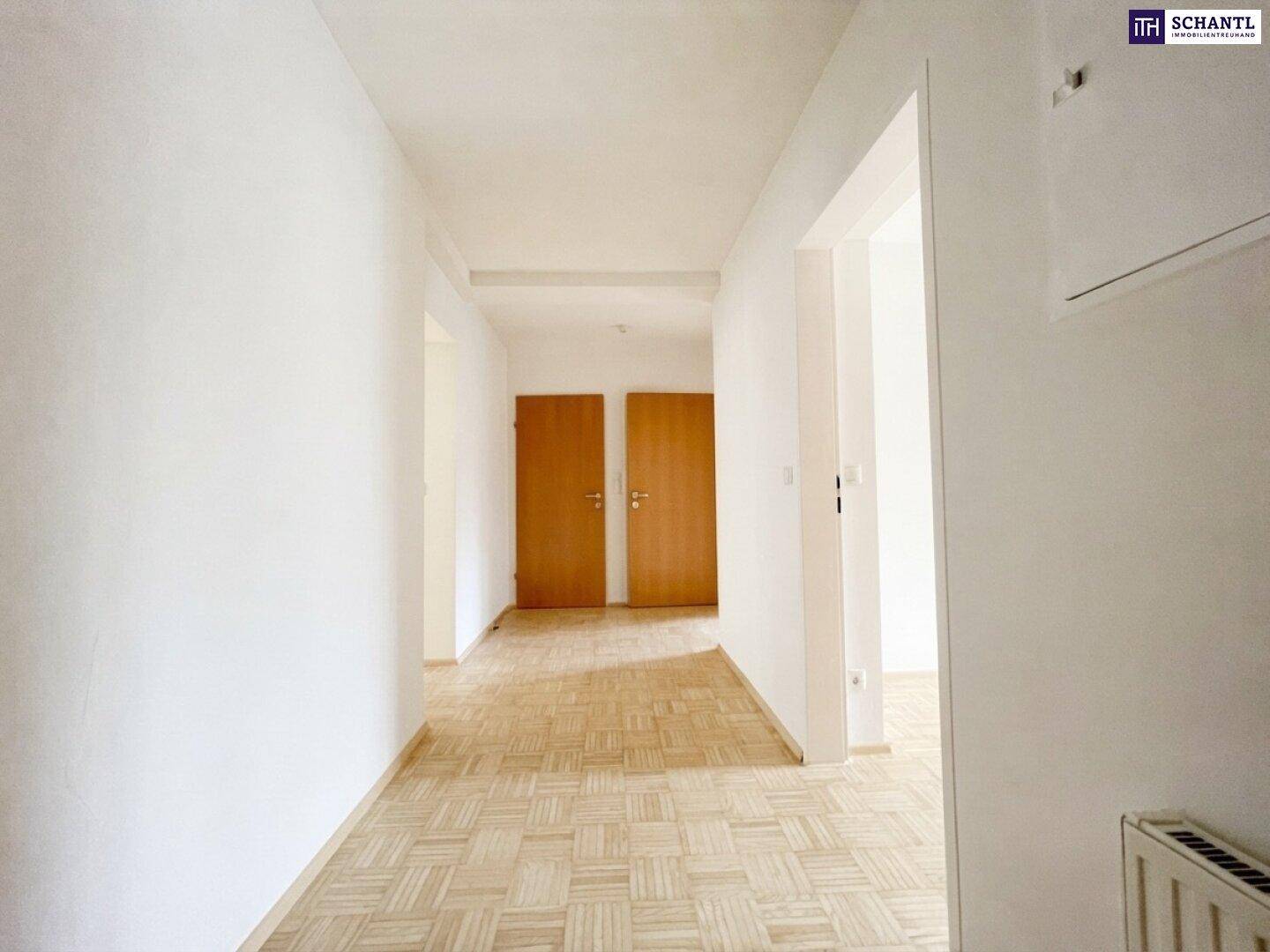 Heller Flur mit Parkettboden und Holztüren, verbindet die verschiedenen Räume der Wohnung.