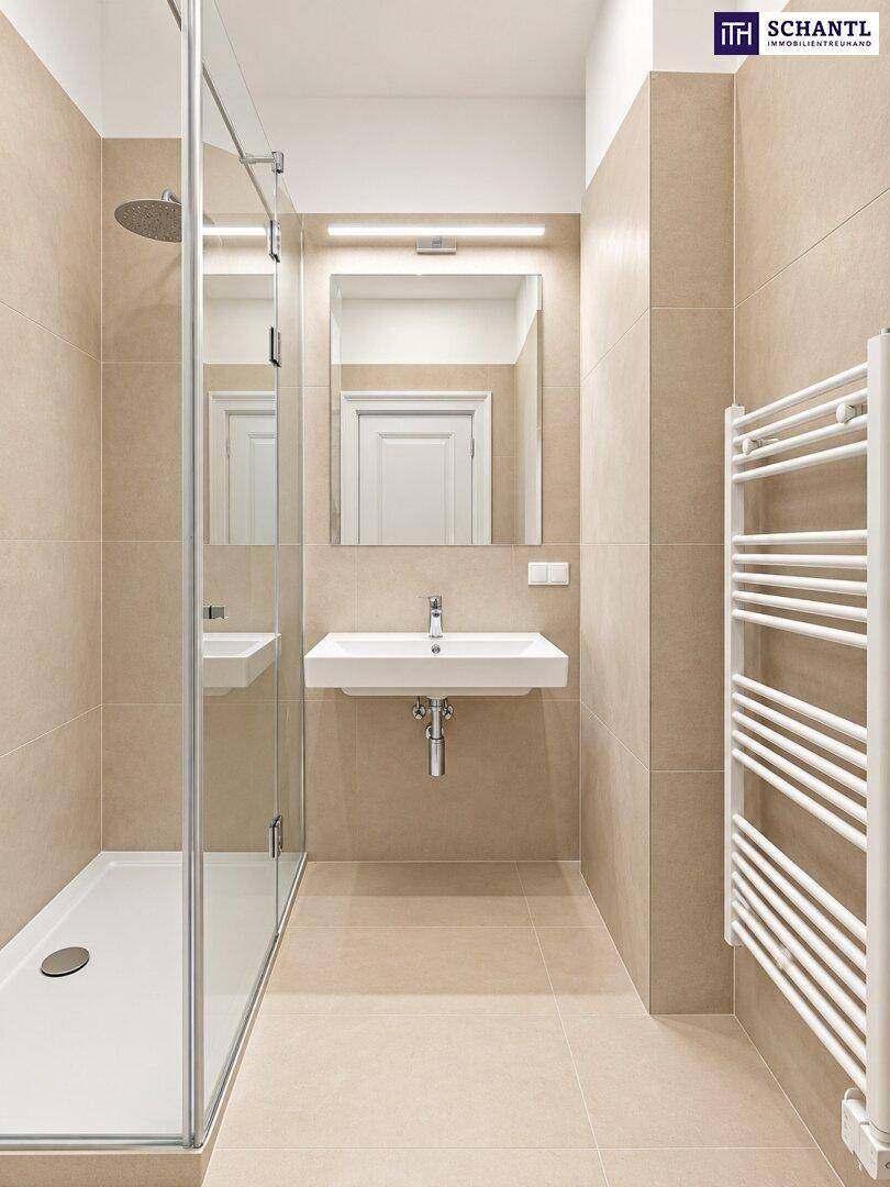 Modernes Badezimmer mit beigefarbenen Fliesen, ebenerdiger Dusche und beheiztem Handtuchhalter.
