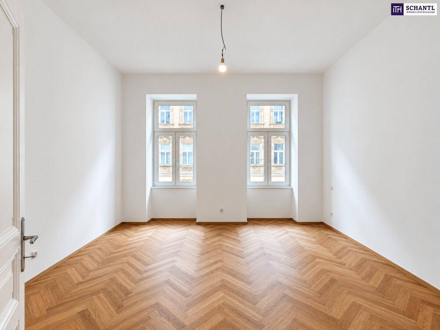 Helles, unmöbliertes Zimmer mit Fischgrätparkett und zwei Fenstern, ideal als Schlaf- oder Arbeitszimmer.