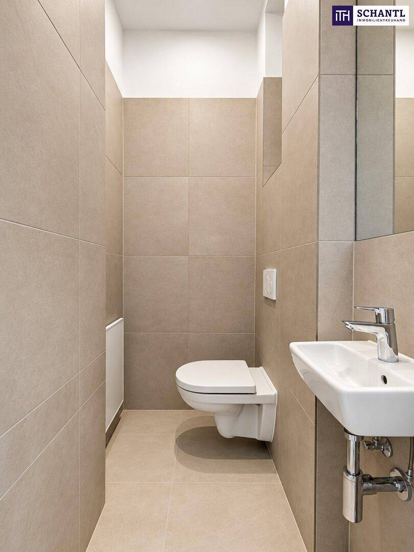 Modernes Gäste-WC mit beigefarbenen Fliesen, wandhängendem WC und kleinem Waschbecken.