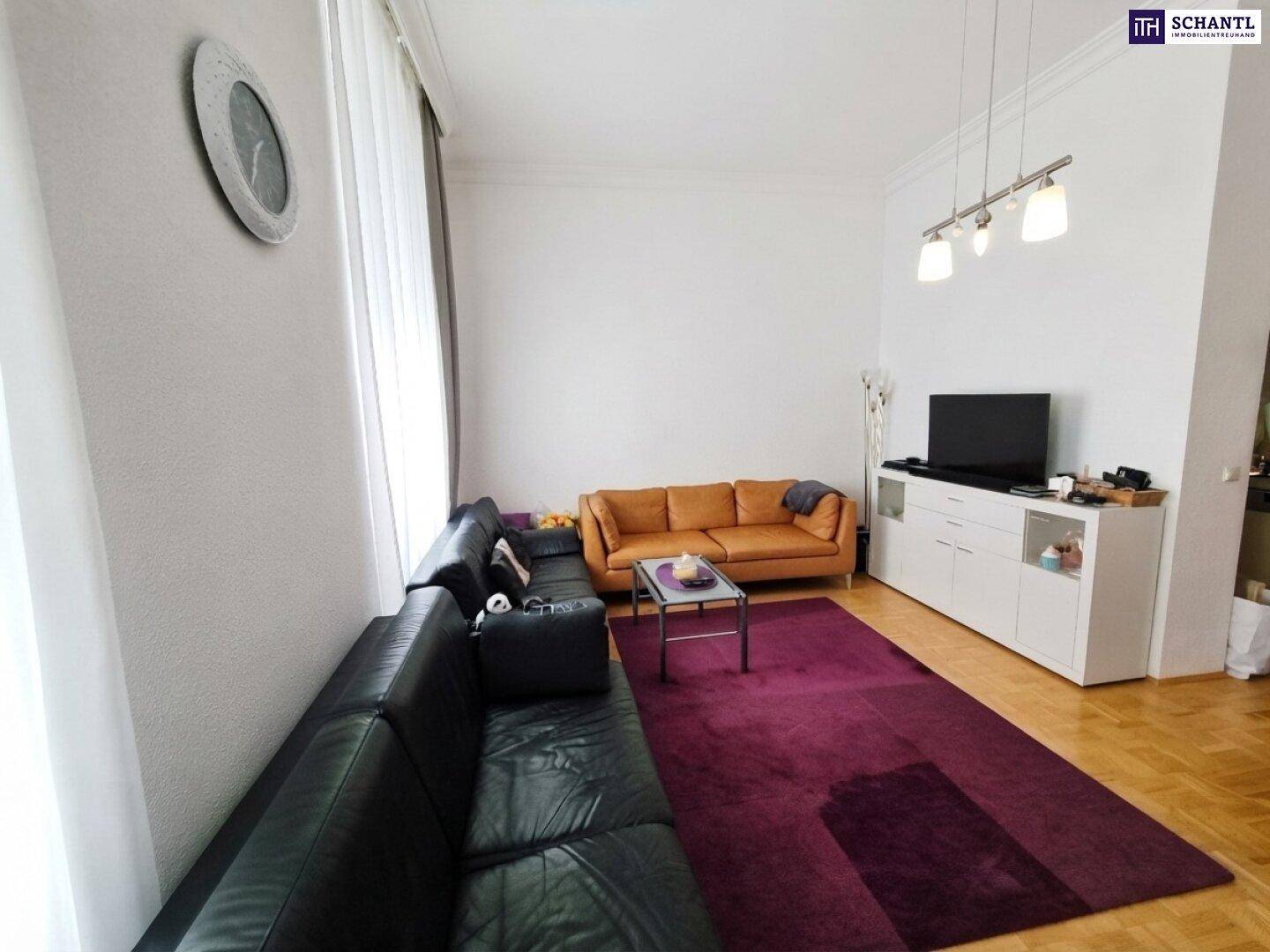 Gemütliches Wohnzimmer mit Parkettboden, zwei Sofas und einem großen Teppich in kräftigem Lila.