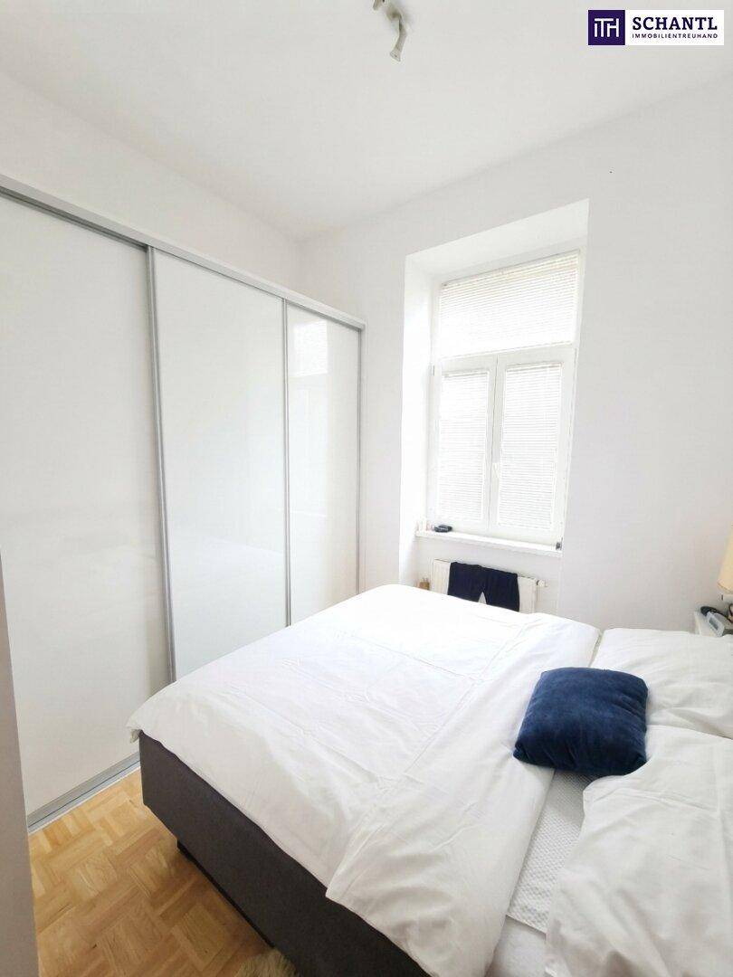 Helles Schlafzimmer mit Parkettboden, großem Bett und integriertem Schiebetürenschrank.