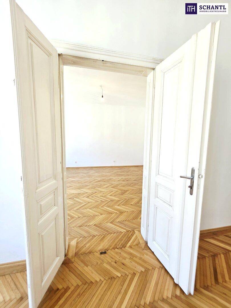 Offene Doppeltür mit klassischem Design, die zu einem weiteren Raum mit Parkettboden führt.