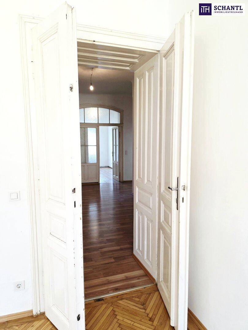 Klassische Doppeltür mit Glaspaneelen, die zu einem Raum mit Holzboden führt.