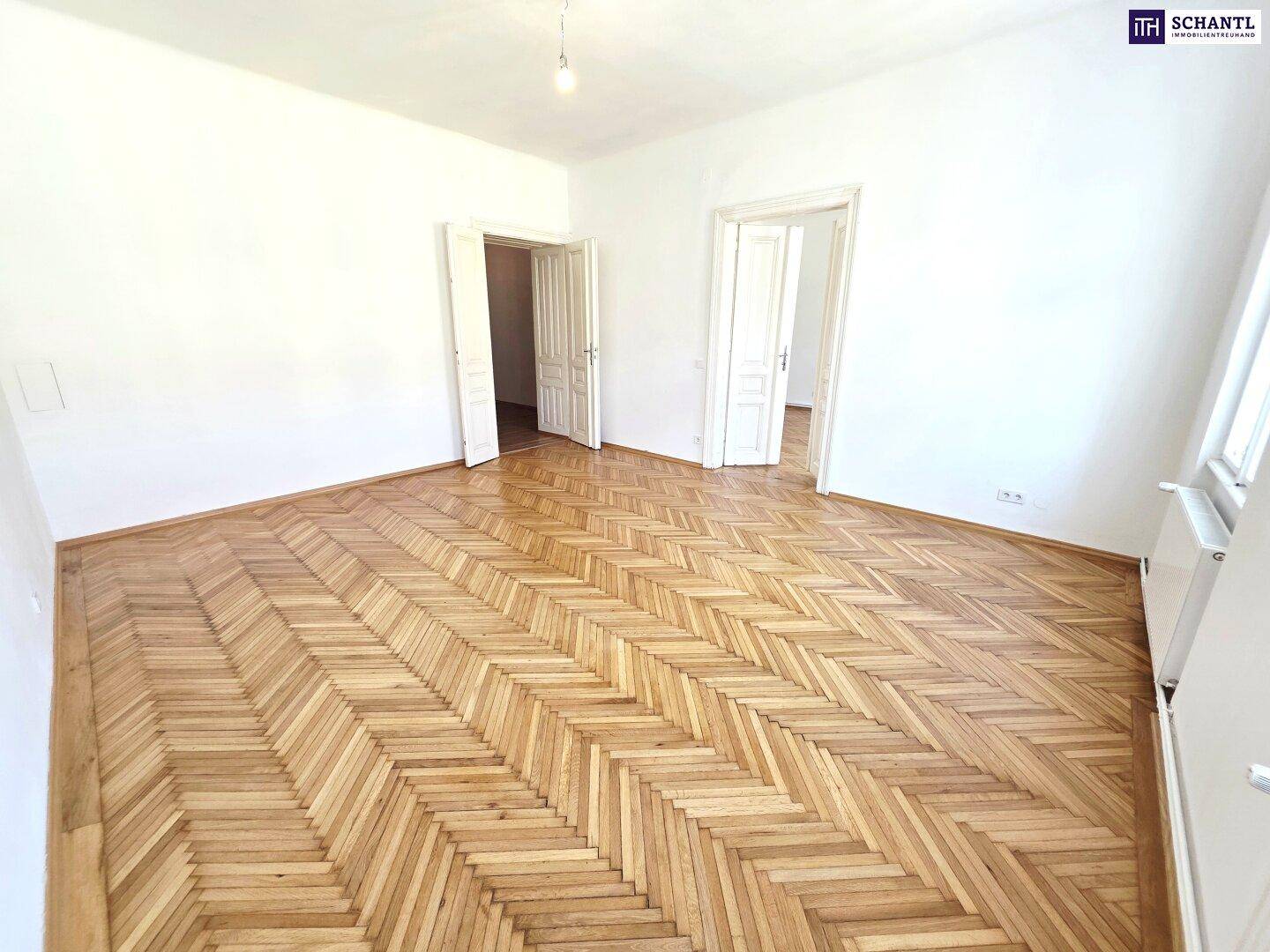 Helles Zimmer mit Fischgrätparkett und zwei Fenstern, ideal für Wohn- oder Schlafbereich.
