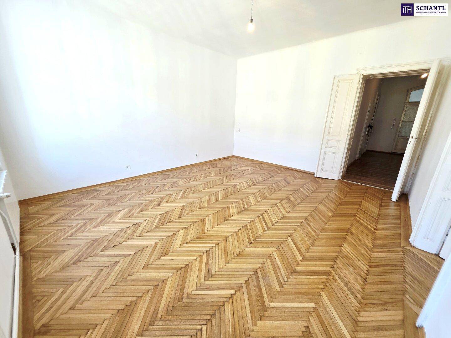 Geräumiges Zimmer mit Fischgrätparkett und zwei Fenstern, bereit zur Einrichtung.