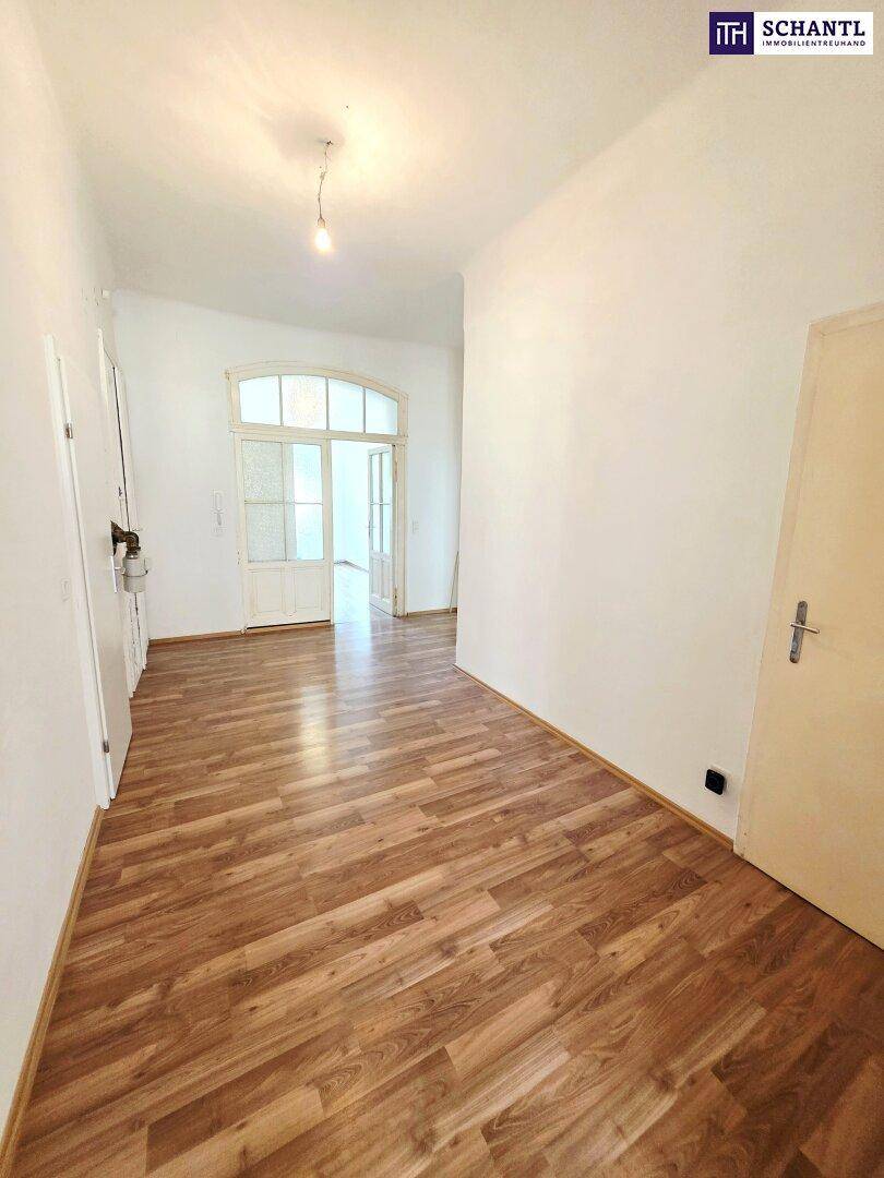 Eingangsbereich mit Laminatboden und einer Tür mit Glaspaneelen, die zu weiteren Räumen führt.