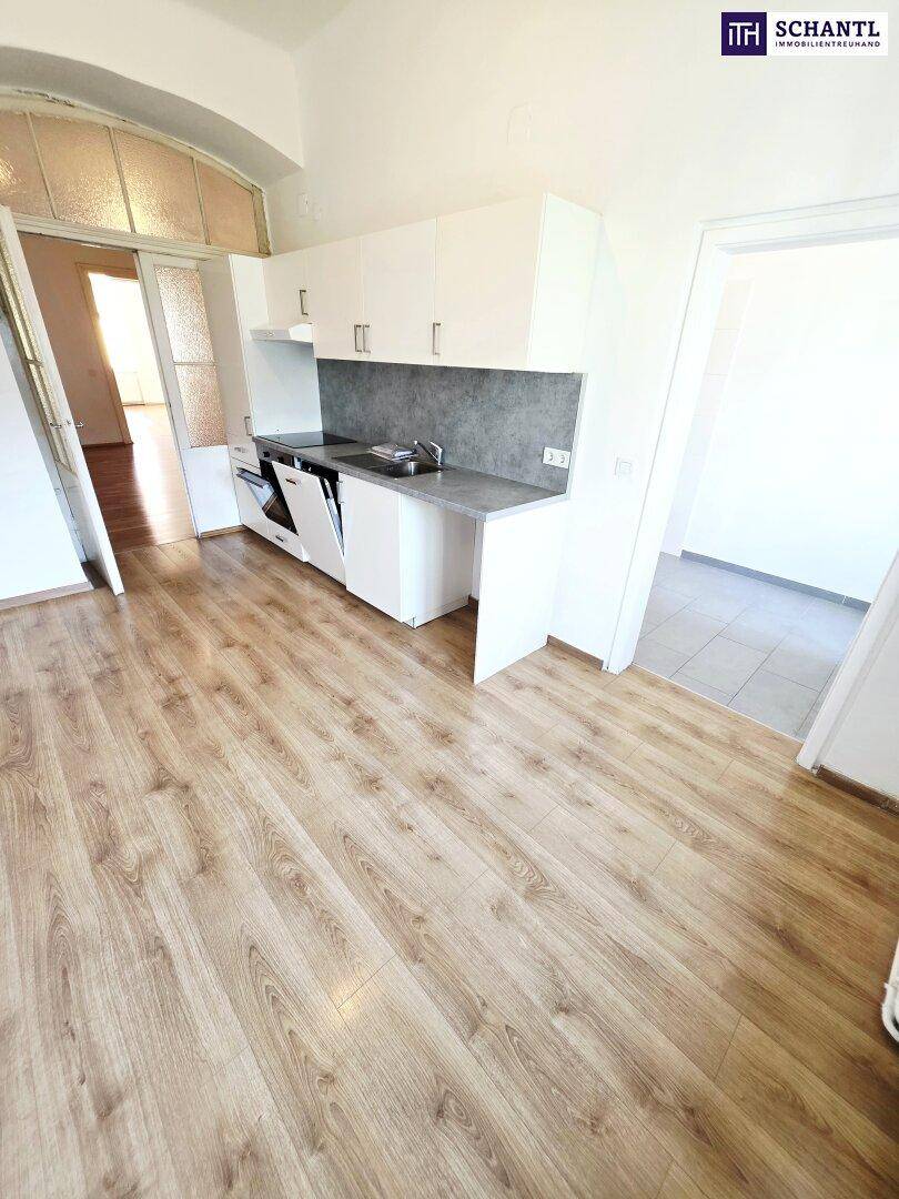 Funktionale Küche mit weißen Schränken, Laminatboden und integrierten Geräten.