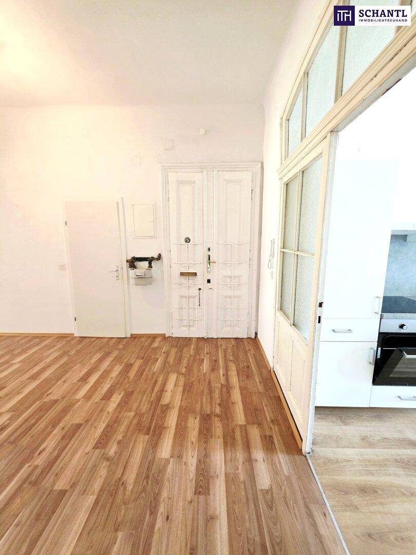 Eingangsbereich mit Laminatboden und Zugang zu einer modernen Küche.