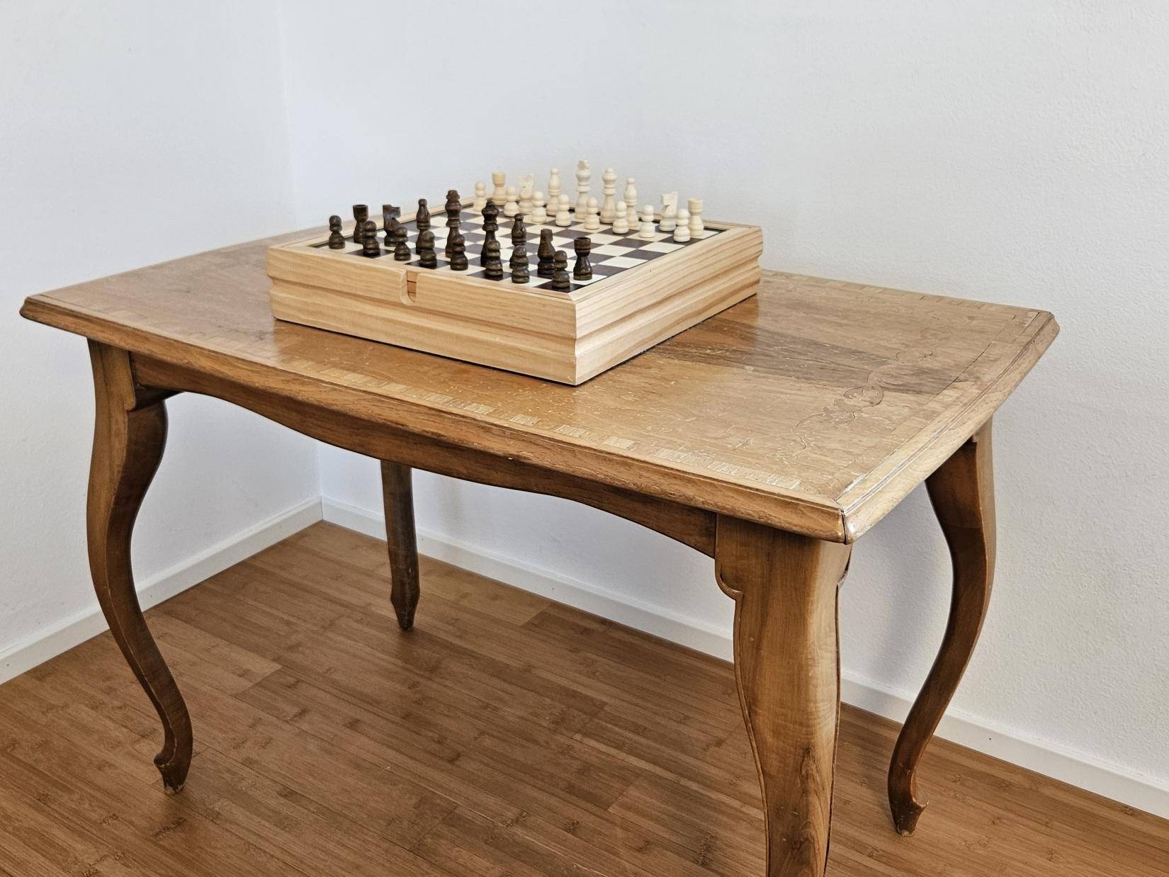 Kleiner Holztisch mit Schachspiel in einem hellen Flurbereich.