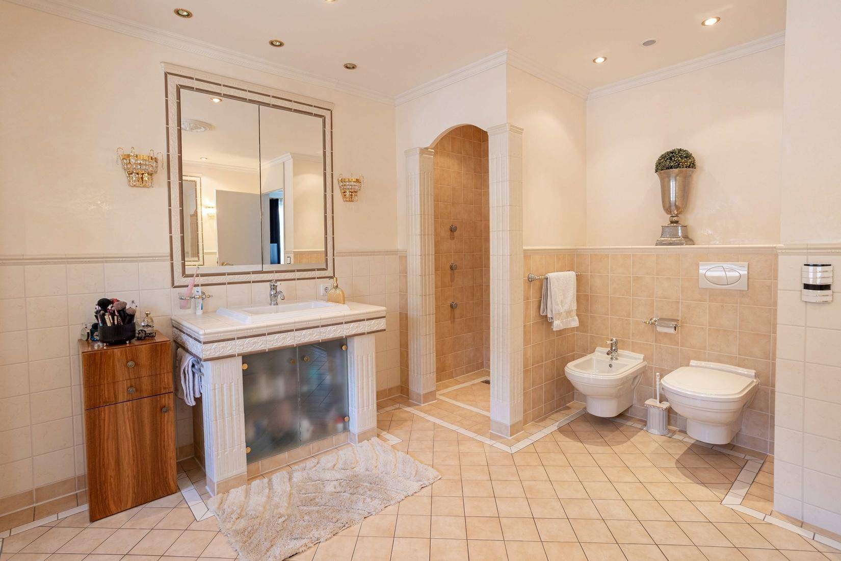 Elegantes Badezimmer mit Dusche, Bidet und WC, in hellen Fliesen gehalten.