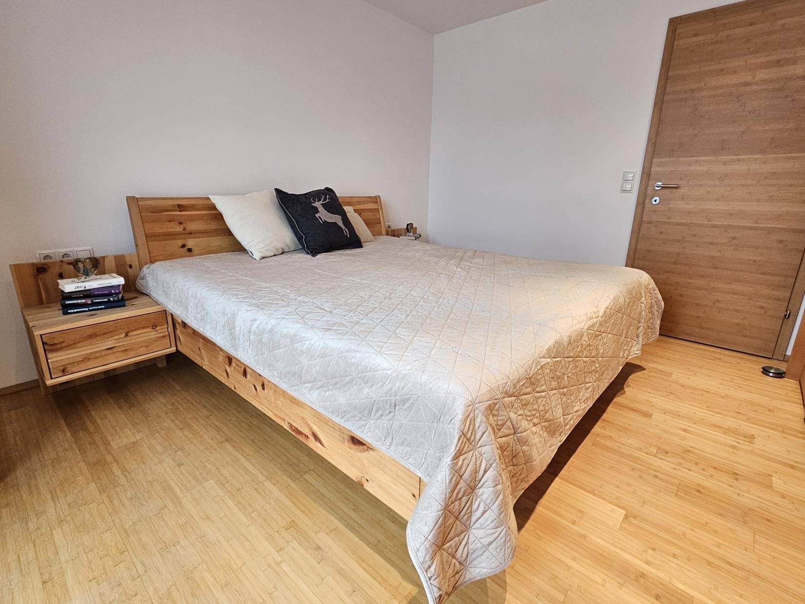Helles Schlafzimmer mit Holzbett und Nachttischen, ausgestattet mit Holzfußboden.