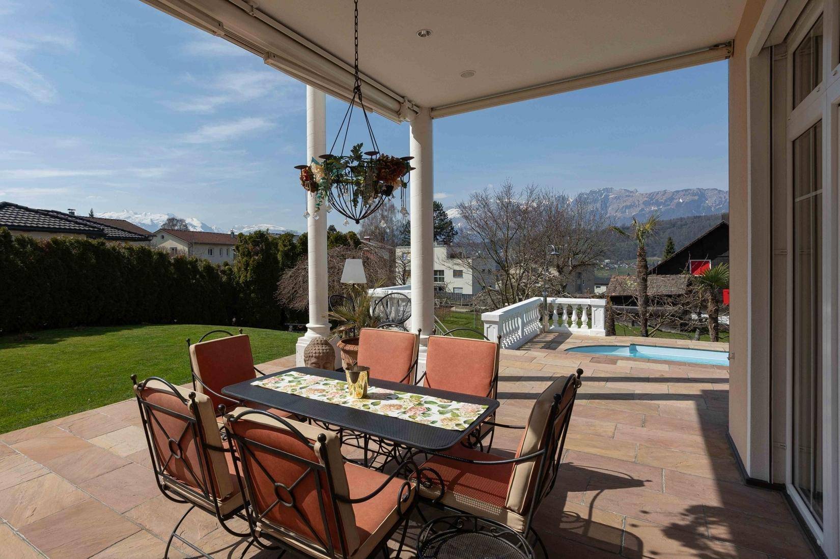 Überdachte Terrasse mit Esstisch und Stühlen, ideal für Mahlzeiten im Freien mit Bergblick.