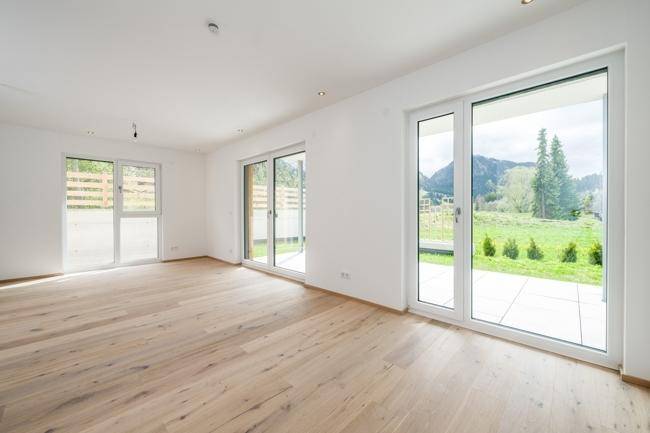 Helles Wohnzimmer mit Eichenparkettboden, großen Fenstern und Zugang zur Terrasse mit Gartenblick.