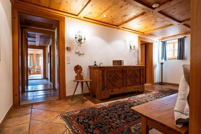 Traditioneller Flur mit Holzbalkendecke, Fliesenboden und einem geschnitzten Holzschrank.