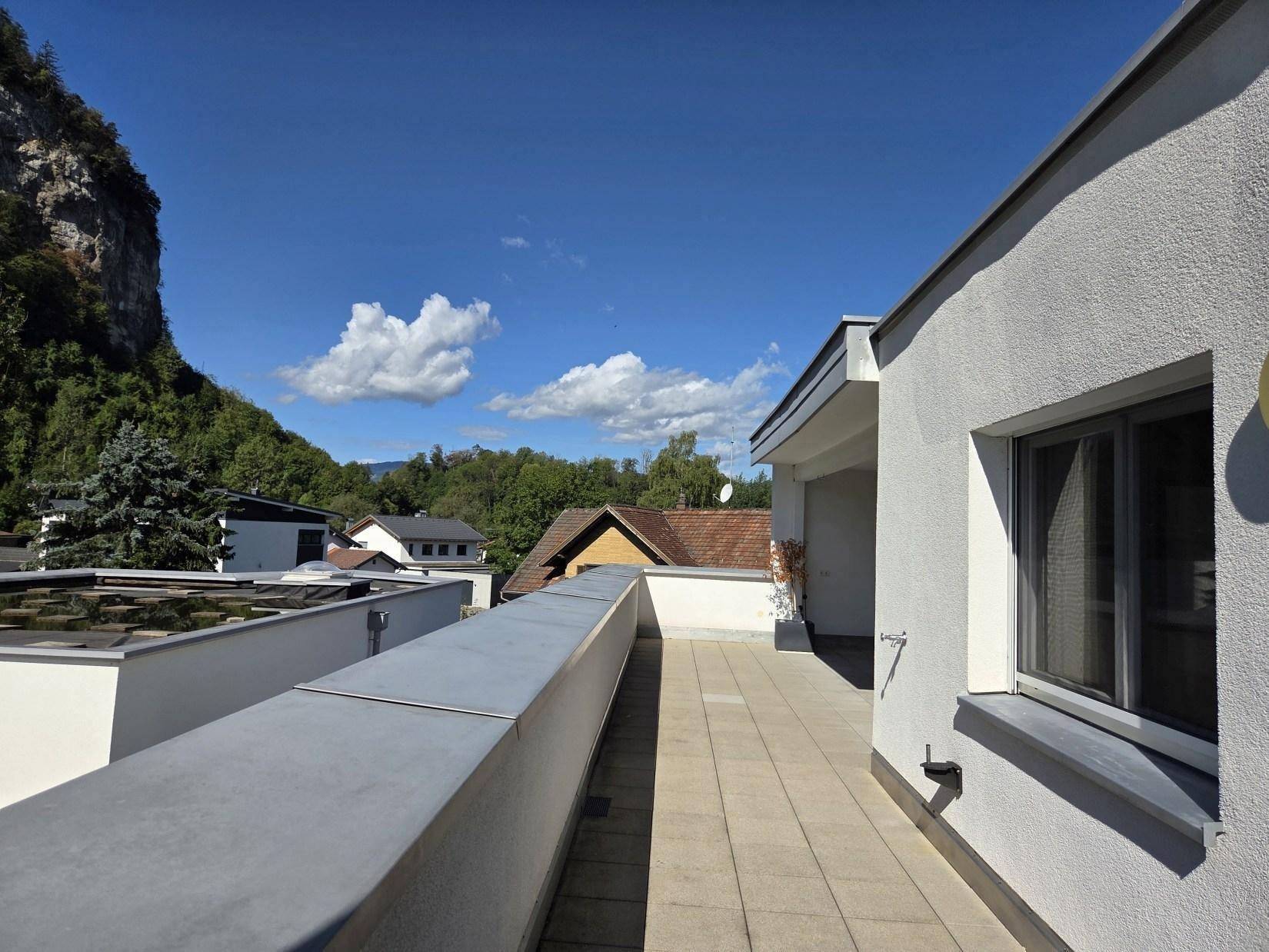 Seitlicher Blick auf die Gebäudefassade mit langem Balkon und Aussicht auf die Umgebung.