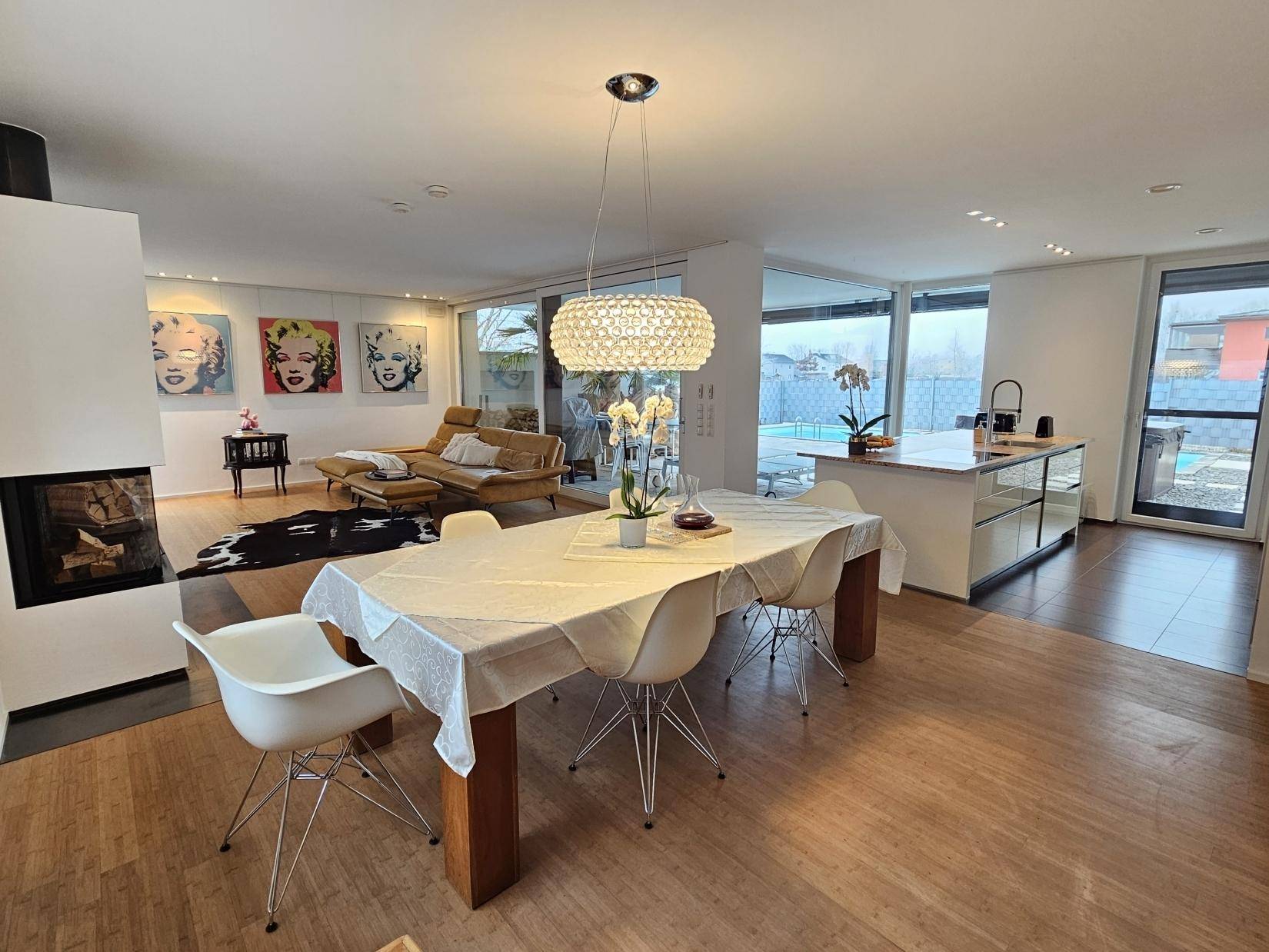 Heller Essbereich mit Design-Hängelampe, offen zum Wohnzimmer und zur Küche.