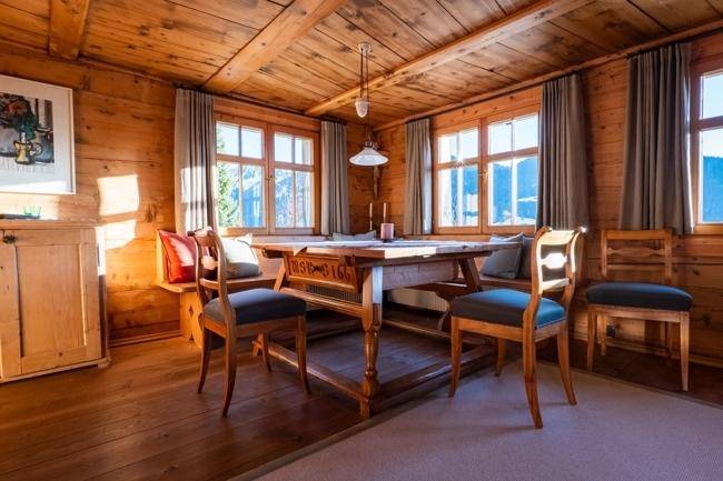 Traditioneller Essbereich mit Holzwänden, Holzbalkendecke und Blick auf die umliegende Natur.