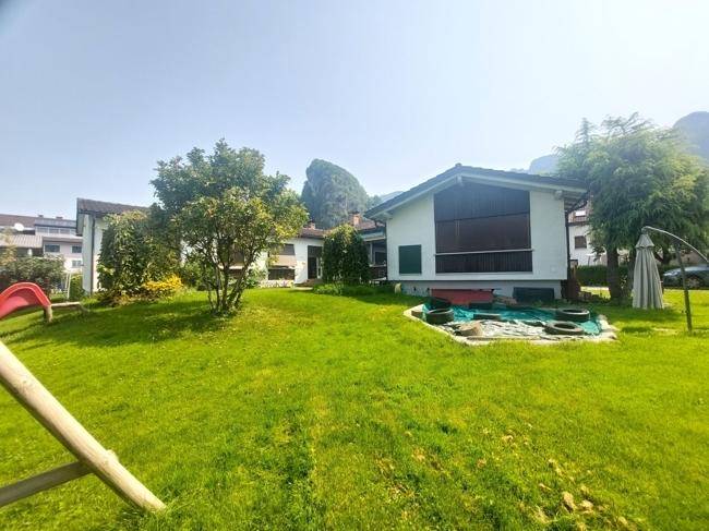 Gepflegter Gartenbereich mit Rasen, Bäumen und einem Haus im Hintergrund, ideal für Kinder.