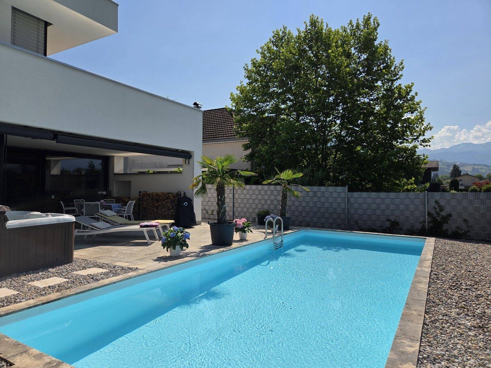 Moderner Außenbereich mit erfrischendem Pool und Whirlpool, umgeben von Palmen und mit Bergblick.