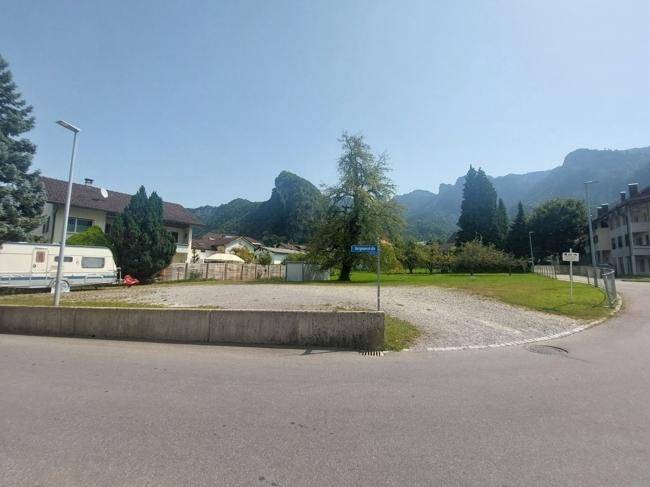 Grundstück von der Straße aus gesehen mit Bergen im Hintergrund und einem Wohnmobil.