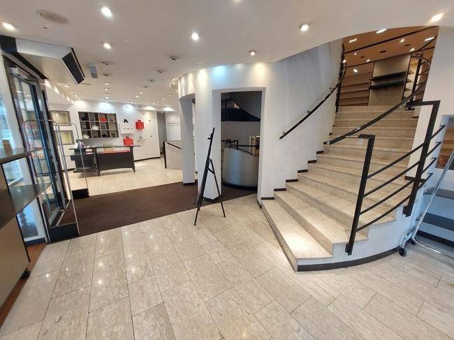 Verkaufsfläche mit einer eleganten Steintreppe, die zu weiteren Ebenen führt, und einem hellen Fliesenboden.