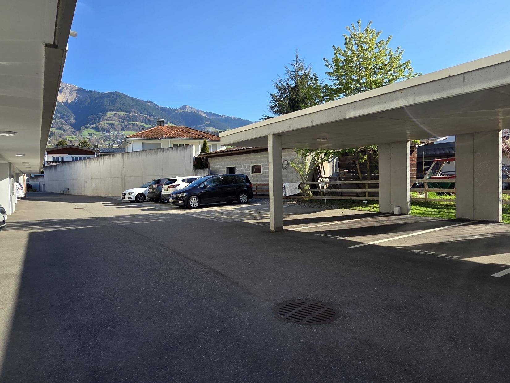 Außenparkplätze unter Carports mit Blick auf die umliegende Berglandschaft an einem sonnigen Tag.